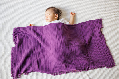 Child resting comfortably with a purple cotton blanket covering them.