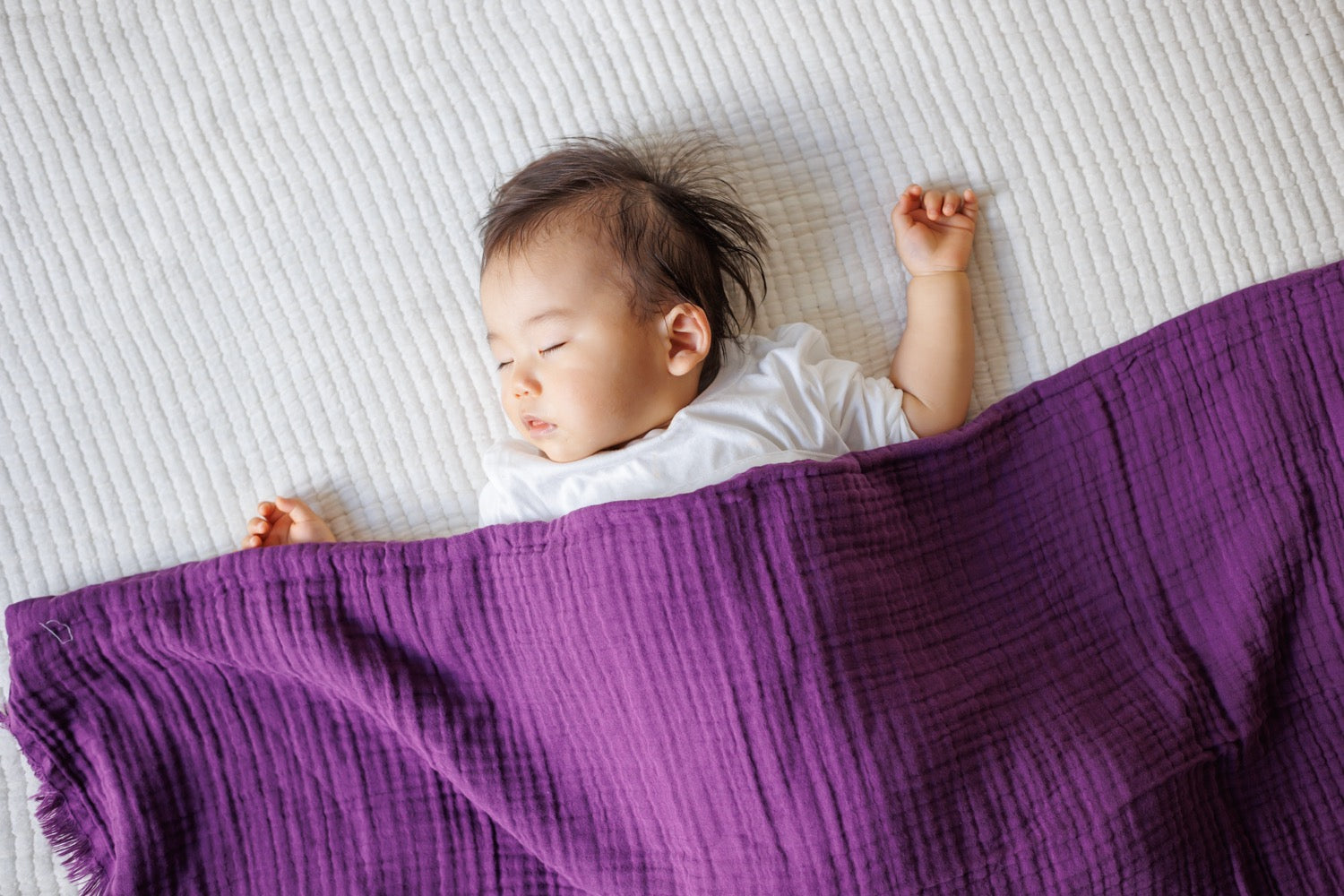 Child resting comfortably with a purple cotton blanket covering them