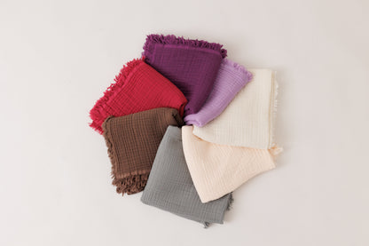 Close-up of organic Turkish muslin blankets in vibrant colors stacked on top of each other.