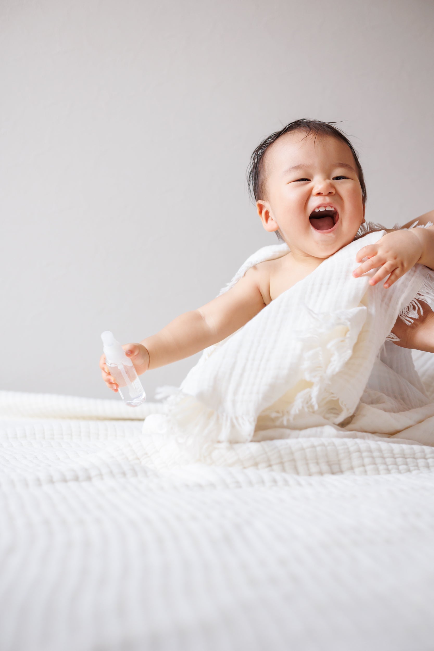 Cream crinkled cotton gauze blanket styled as a throw on a bed, highlighting its use as cozy decor