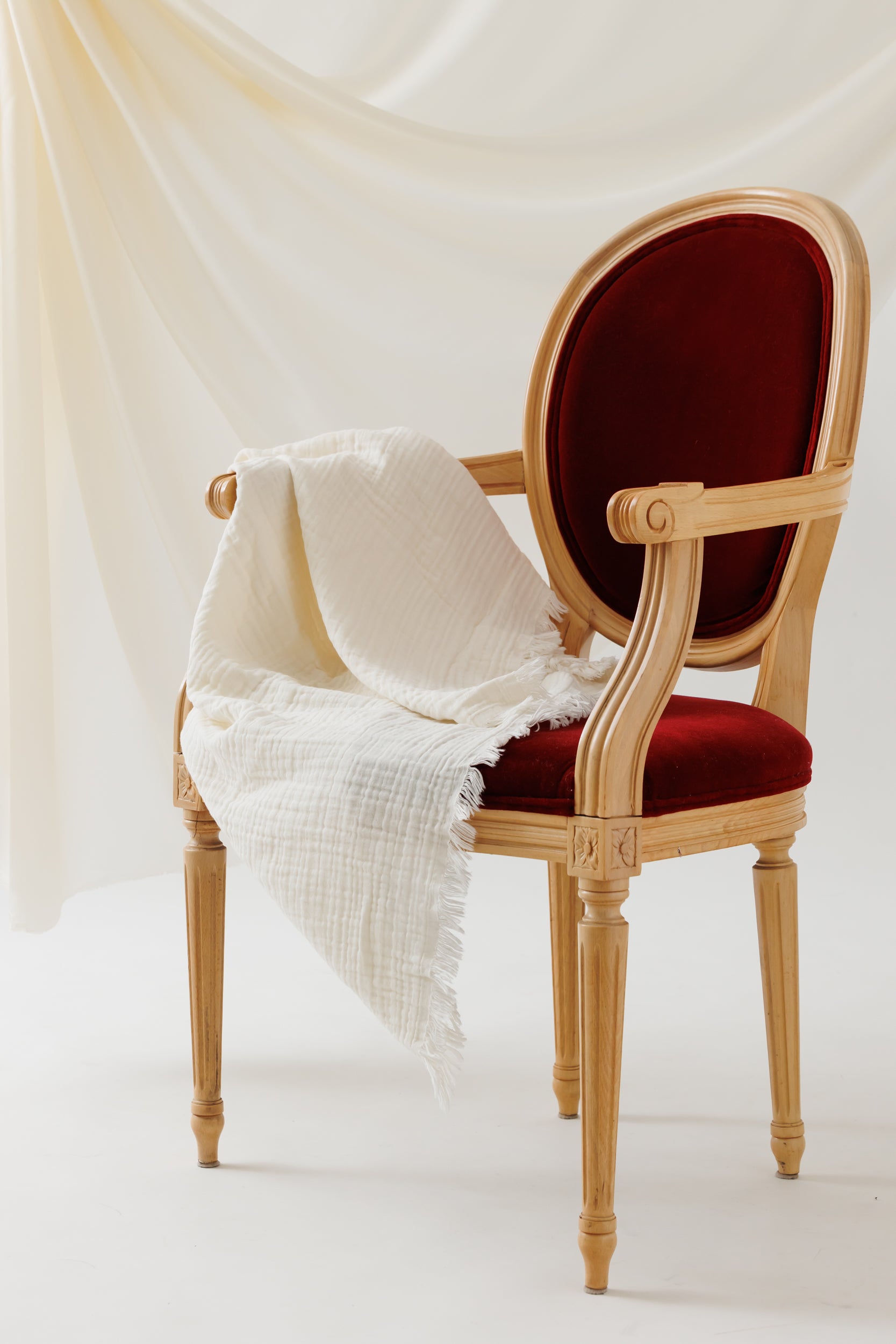 4-layer cream muslin cotton blanket draped over a chair, illustrating its natural texture and soft drape