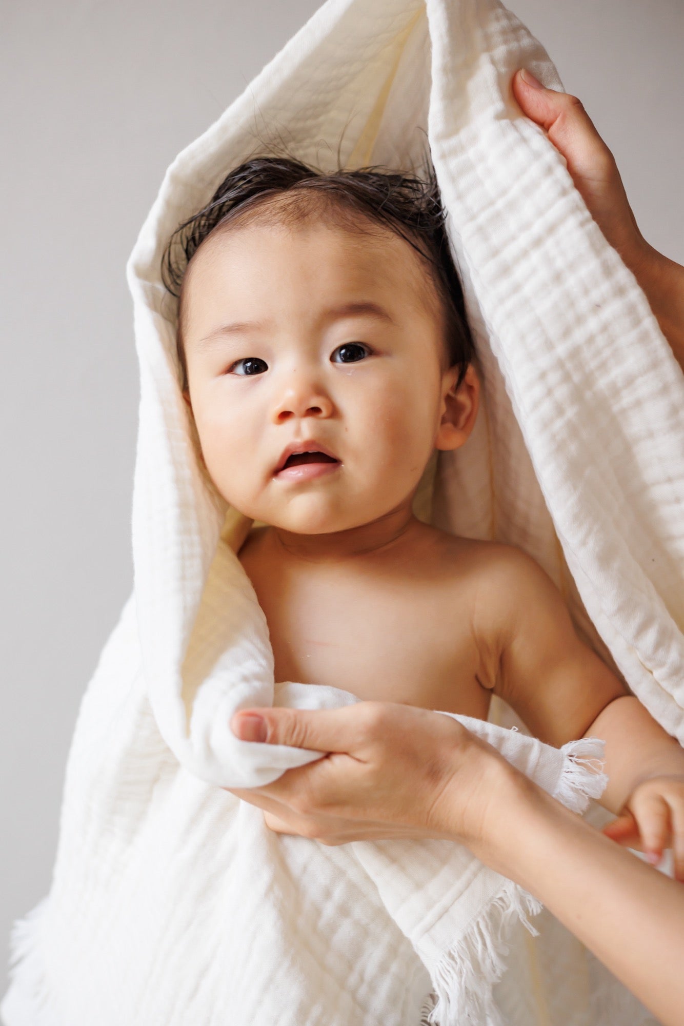 Folded cream-colored organic muslin blanket, showcasing its soft and delicate crinkled texture